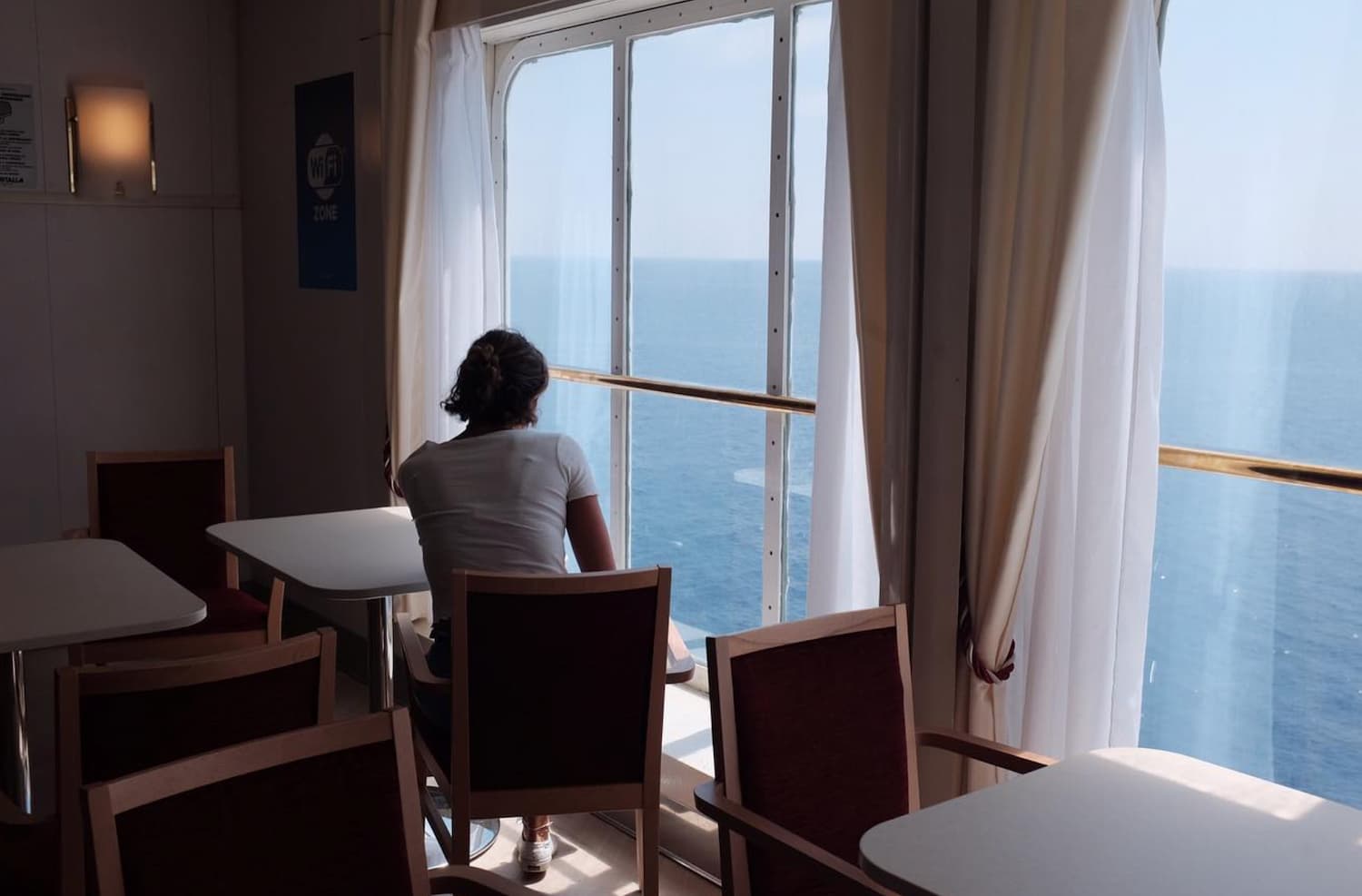Yvan Canal Street 55 — woman sitting alone facing the sea through a window